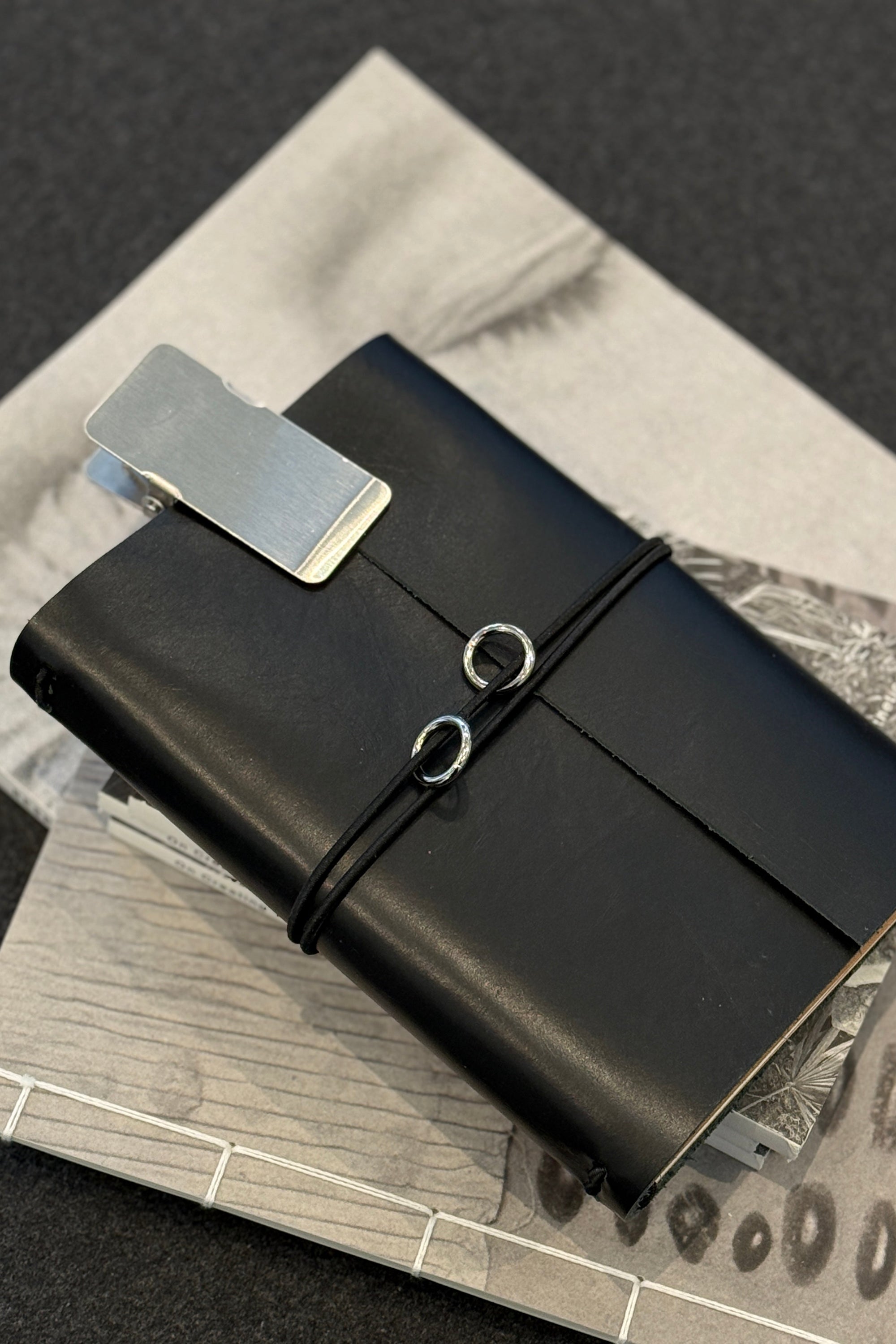 Black leather journal with a silver clip on a textured surface