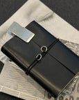 Black leather journal with a silver clip on a textured surface